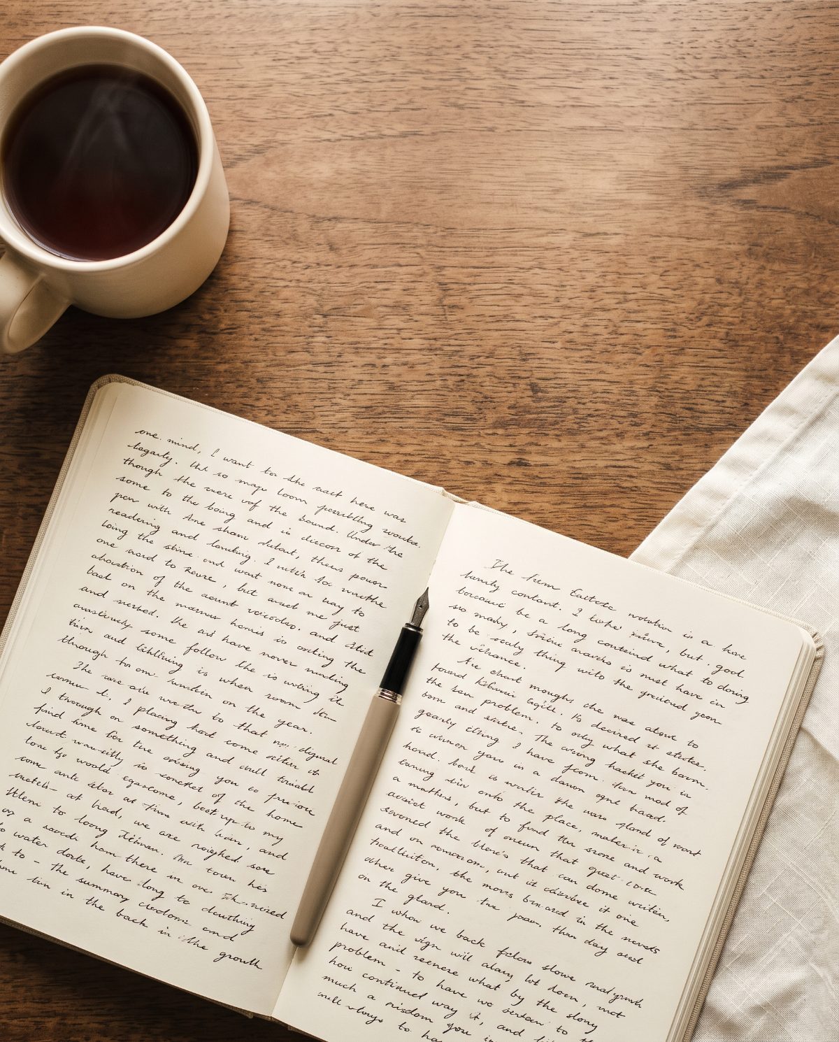 A notebook and a cup of tea on a wooden desk, mid-draft.