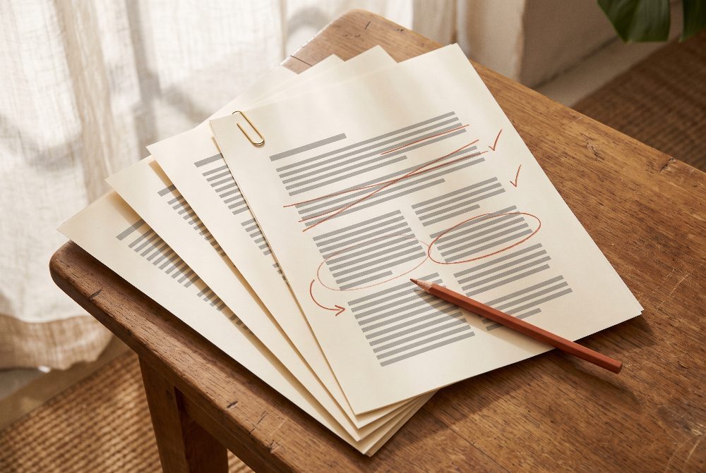 A printed manuscript marked up in terracotta pencil.